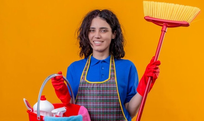 young woman with a broom and a bucket full of chemical bottles and cloth mops