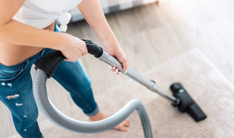 Women in blue jeans and white t-shirt vacuuming
