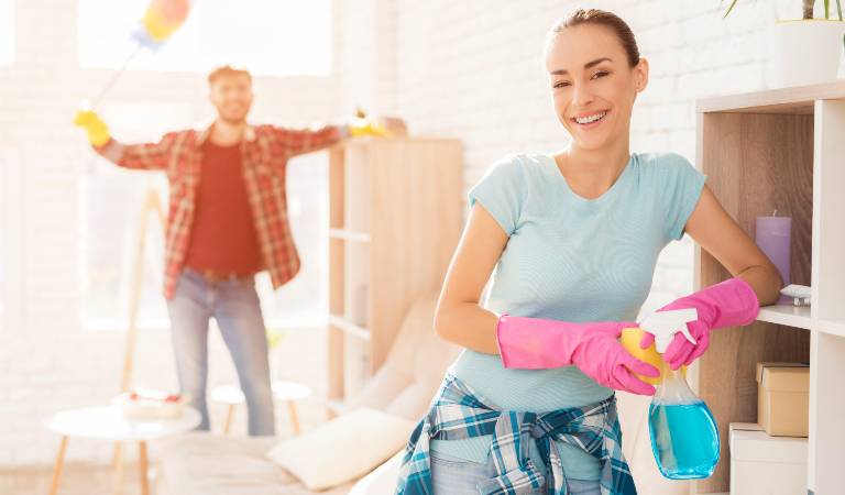 Woman in pink gloves holding a bottle in her hand and smiling.