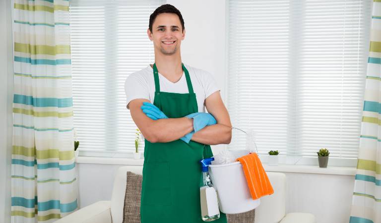 Man in white-green dress and blue gloves standing with white basket.