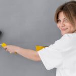 Woman in white top holding a cleaning brush and looking at front.