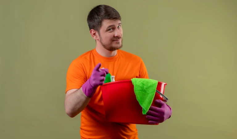 Man in orange t-shirt holding a red basket in his hand and pointing his fingure.