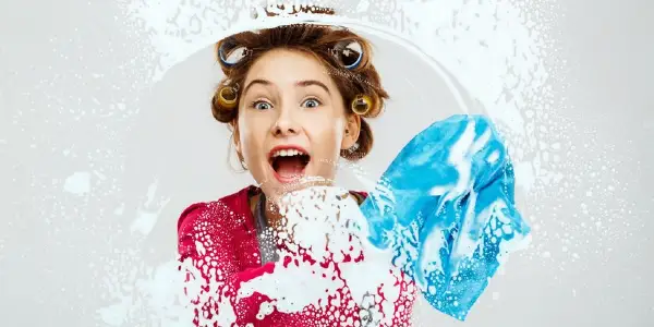 Woman in red top cleaning mirror with a blue cloth.