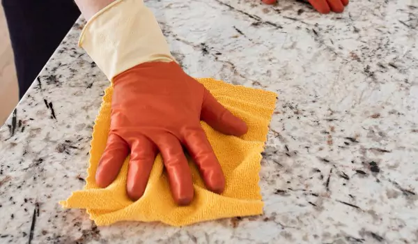cropped picture of a person cleaning a granite surface