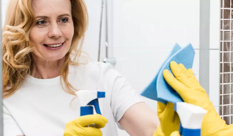woman cleaning a mirror with a cleaning spray