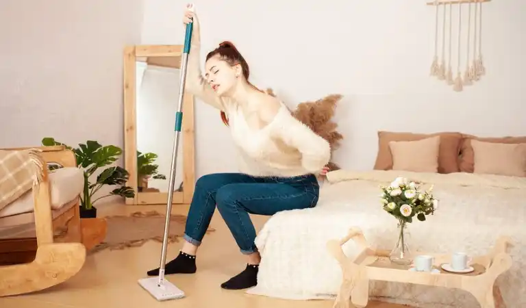 Lady on bed suffering from pain holding a cleaning stick in her hand.