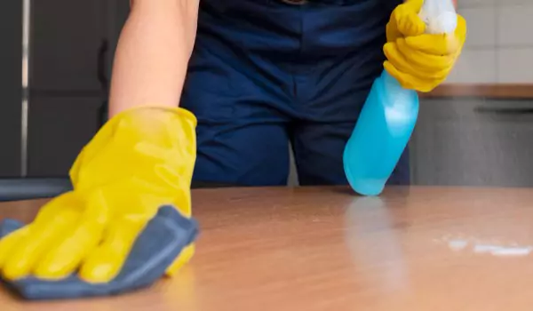 person disinfecting a wooden surface