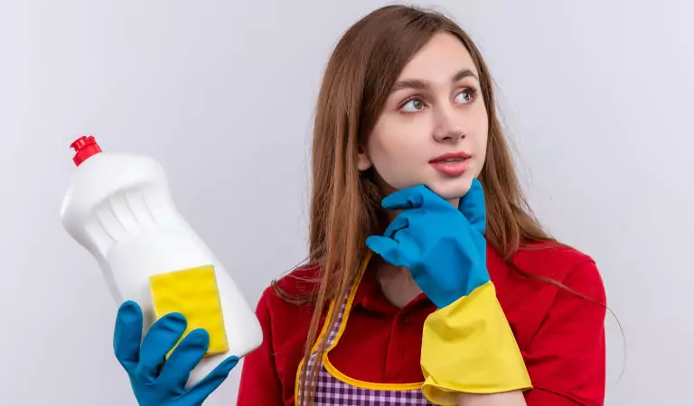 woman with a chemical cleaner and a cleaning sponge thinking about something
