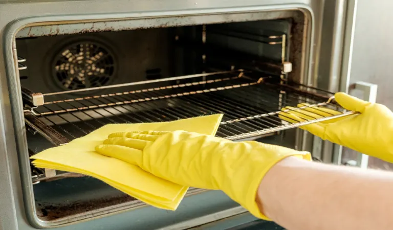Male hand with gloves cleaning oven