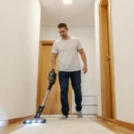 A man is vacuuming hallway at home