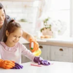 A mother and daughter are cleaning a kitchen table together