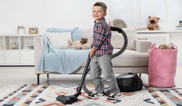Little helper cute boy vacuuming room at home