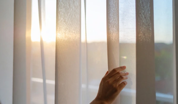 A person holding a vertial window blind