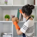 Housekeeping professional cleaning and organising office bookshelf with care