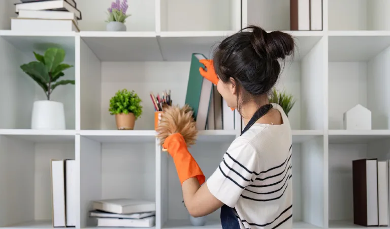 Housekeeping professional cleaning and organising office bookshelf with care