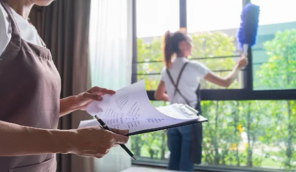 Midsection of woman looking at clipboard against colleague cleaning window