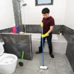 Young man using brush to cleaning the tile in the bathroom