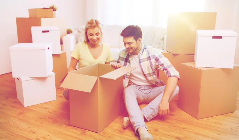 Moving, people, repair and real estate concept - smiling couple looking into big cardboard box at new home